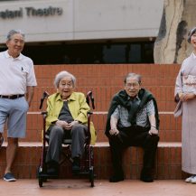 group of fashionable older adults posing for the camera against brick stairs