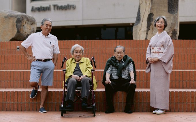 group of fashionable older adults posing for the camera against brick stairs