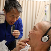 Son holding card to father in hospital bed that says 