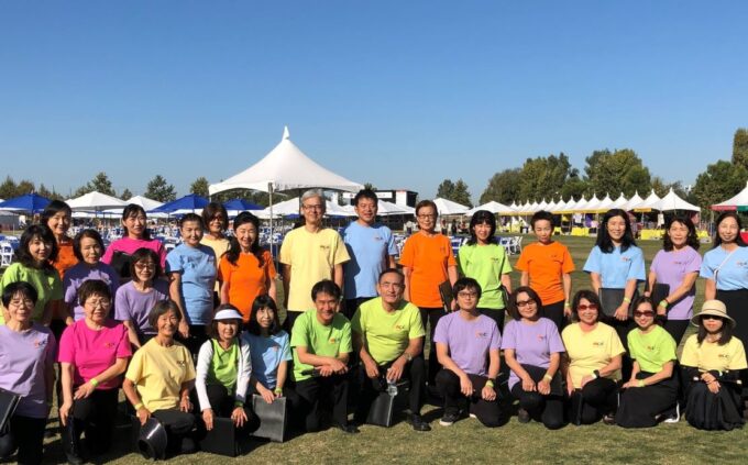 group picture of 28 people outside wearing different colored rainbow shirts