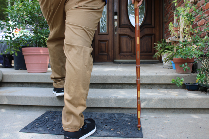 person's legs walking up stairs while holding a cane