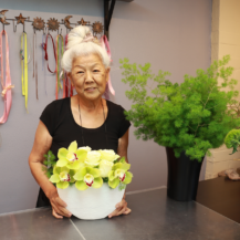 woman florist posing with flower arrangement and greenery