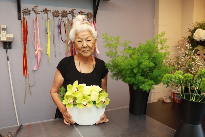 woman florist posing with flower arrangement and greenery
