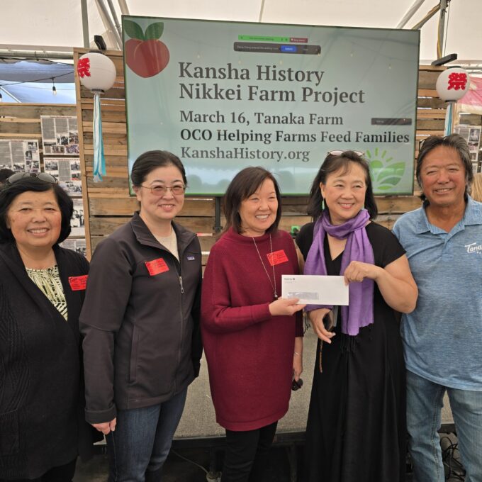 Five people smiling and two people are holding up a envelope