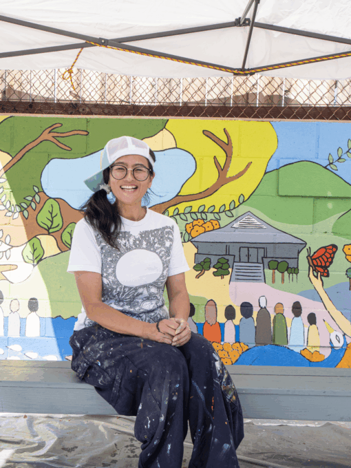 a woman sitting by a mural