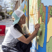 a woman painting a mural on a wall