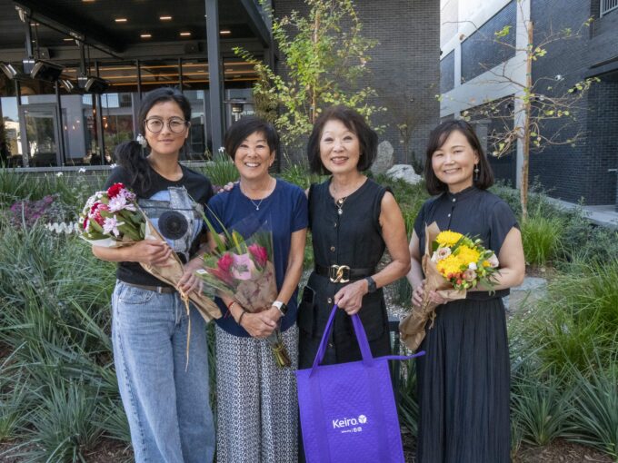 four women holding a purple bag and flowers