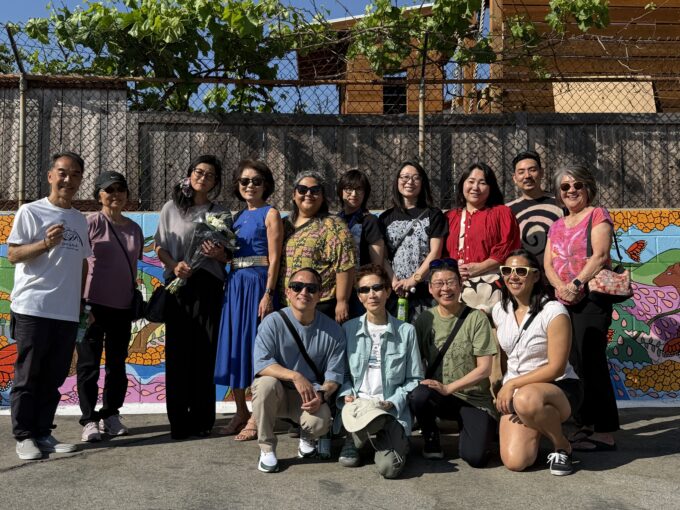 a group of people posing in front of a mural