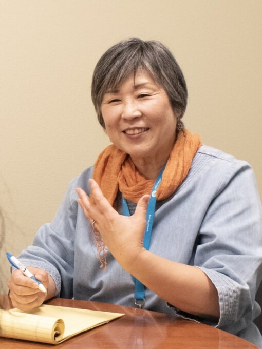 woman with short hair writing on a notepad with pen