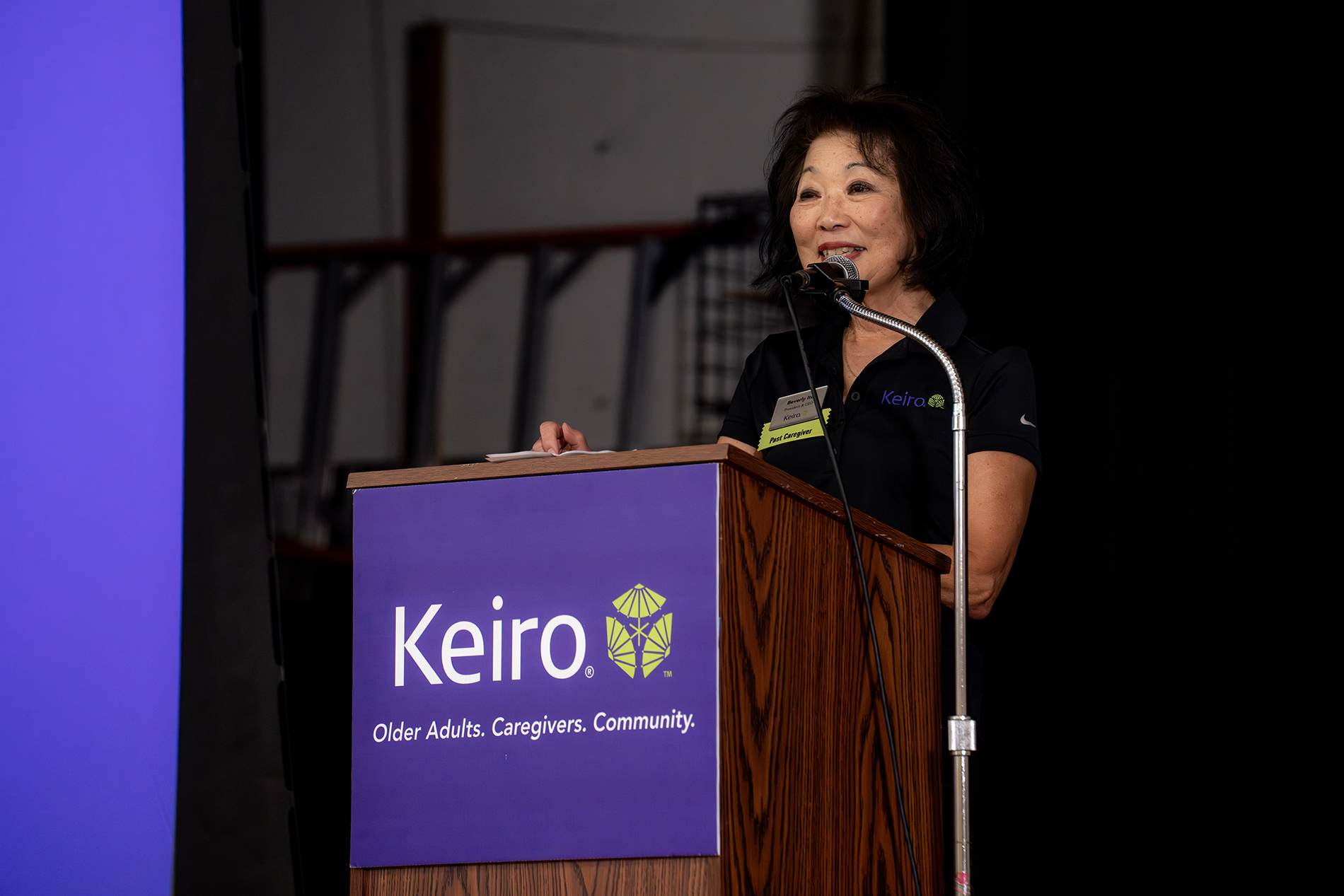 Beverly Ito speaking at Keiro podium into microphone