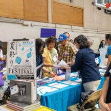 a group of women talking with a woman in blue button down by a blue table