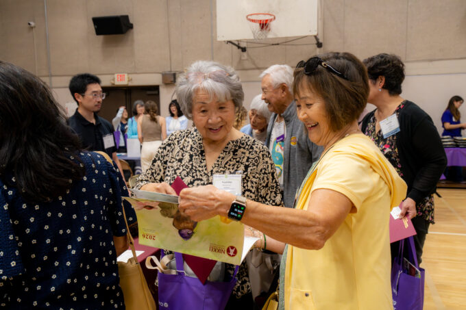 a woman in yellow and a woman in printed black shirt smiling at a camera
