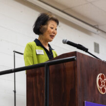 woman wearing green talking into mic at podium