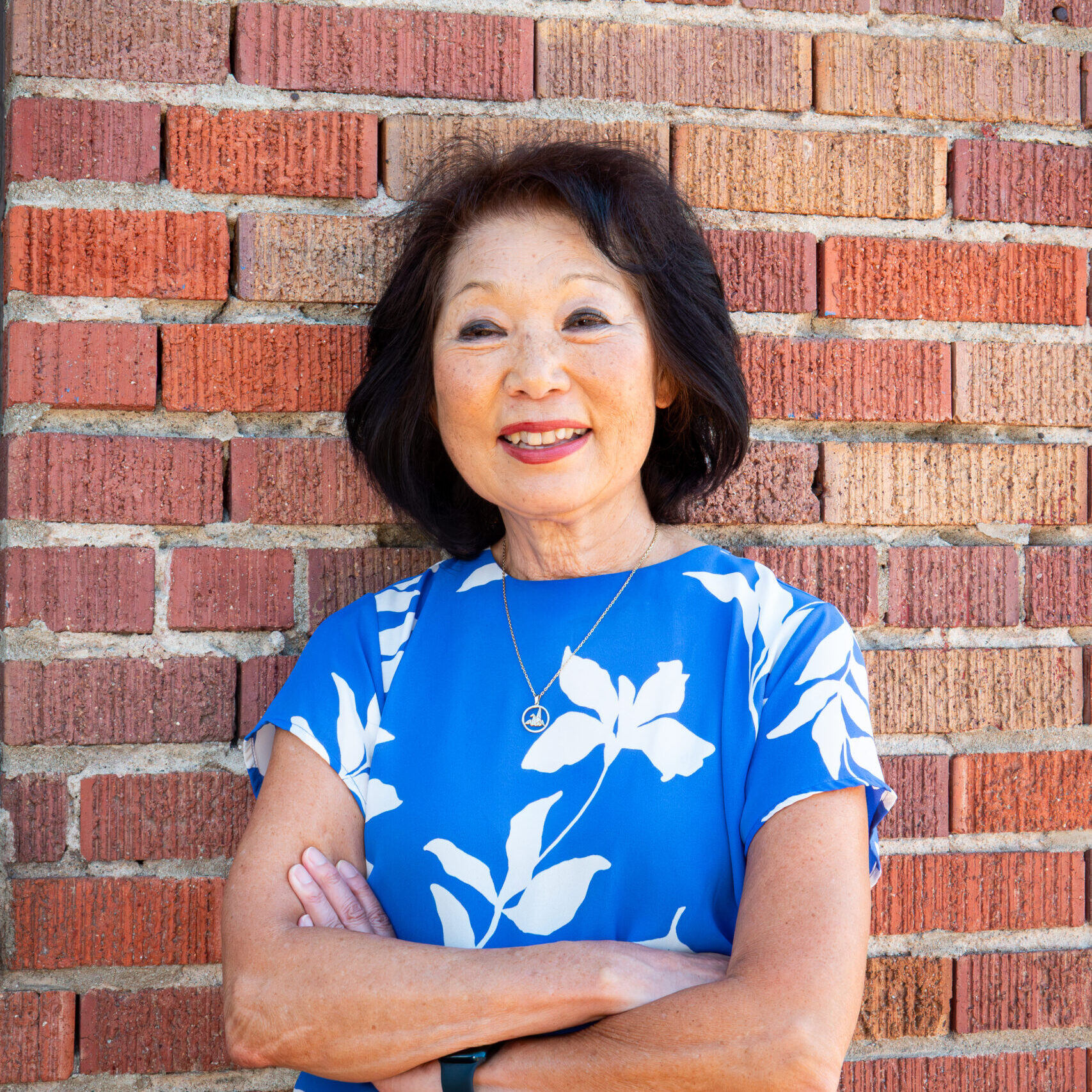 Beverly Ito standing in front of brick wall with arms crossed