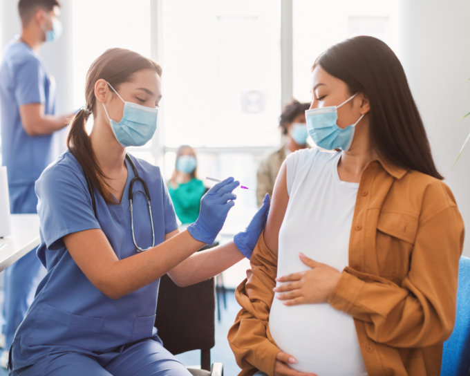 female nurse giving a shot to a woman who is pregnant