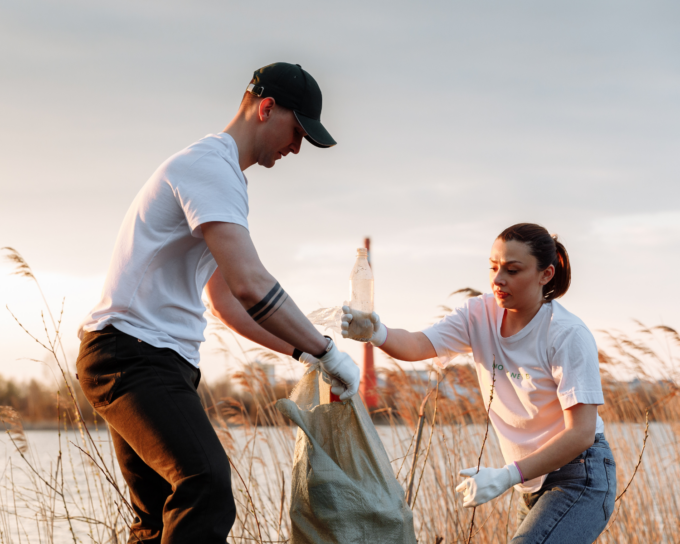 man in white shirt holding bag while woman in white shirt with plastic bottle