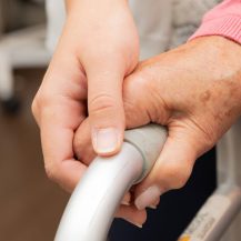 Caregiver's hand on patient with walker
