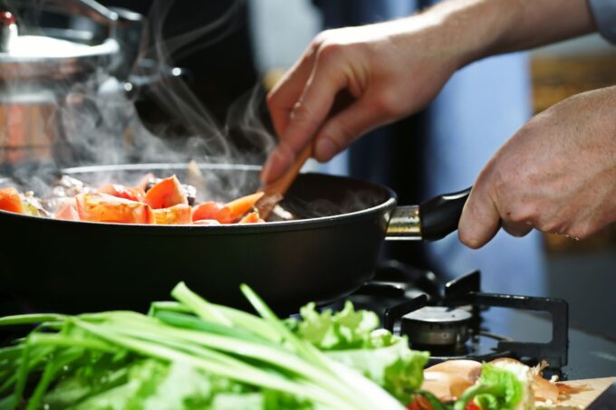 hands stirring food in a pan