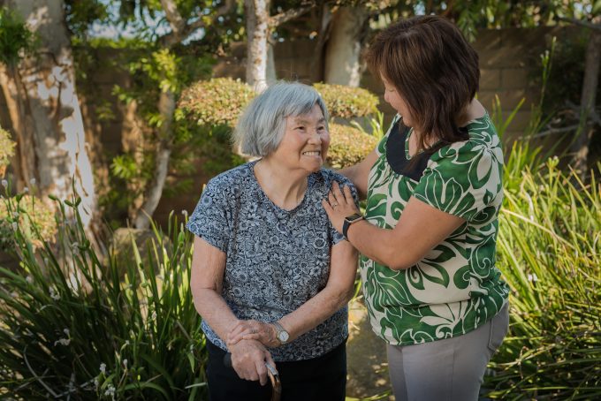 older lady sitting down laughing with woman standing