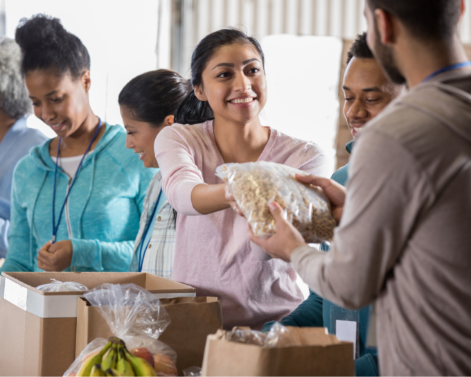 woman in pink shirt giving a bag of food to a male