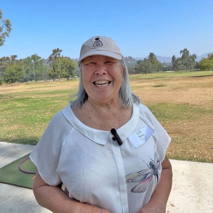woman outside smiling wearing baseball cap and white shirt