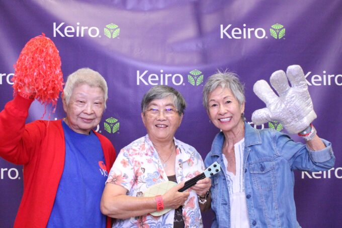 three women posing at photo booth with props