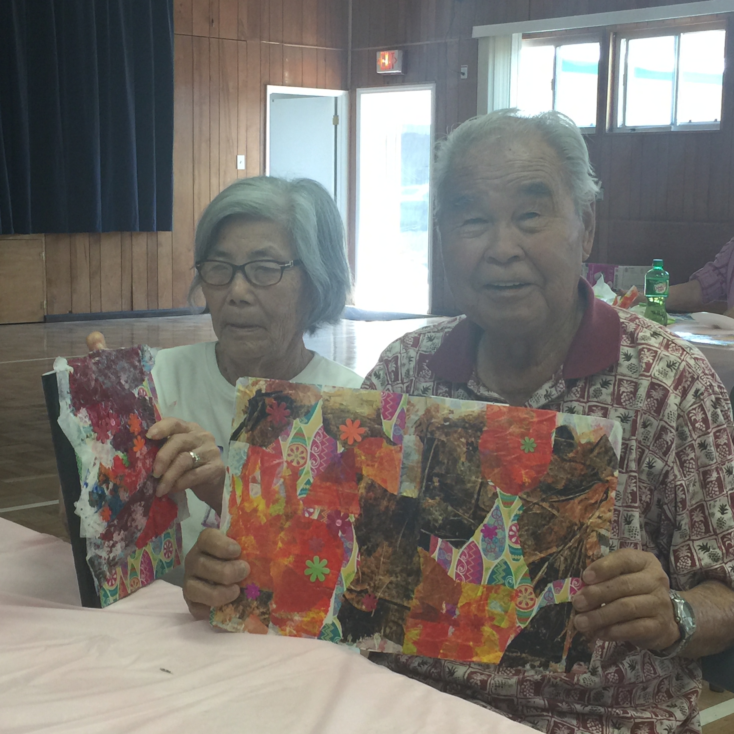 Two older adults display their handmade art