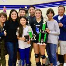 family smiling while one person is holding trophies