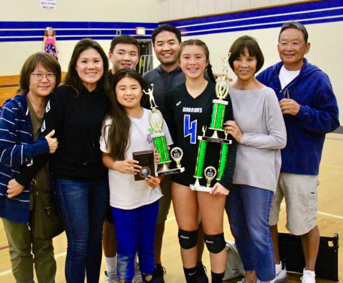family smiling while one person is holding trophies