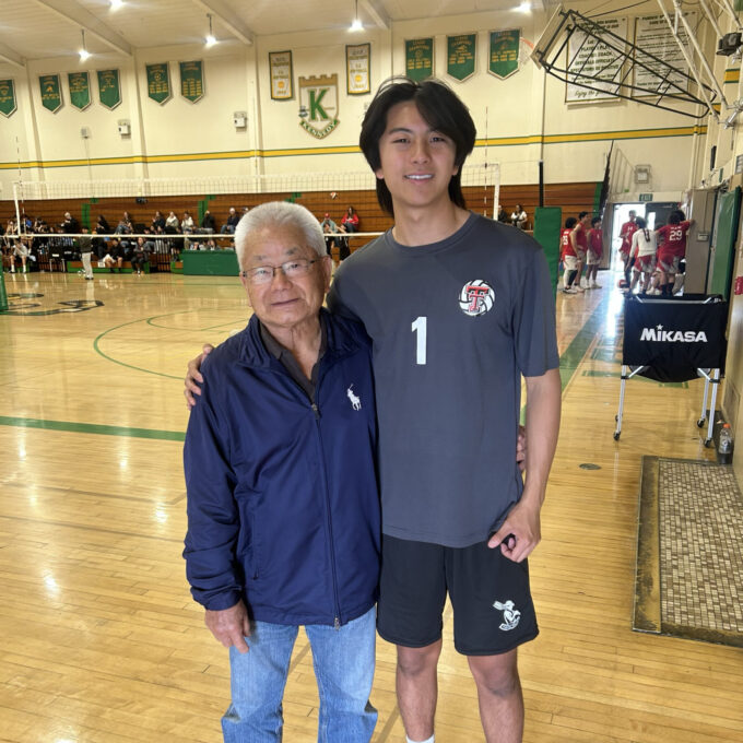 grandpa standing with grandson in a school gym