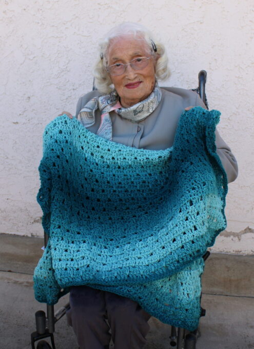 older adult woman holding crochet blanket