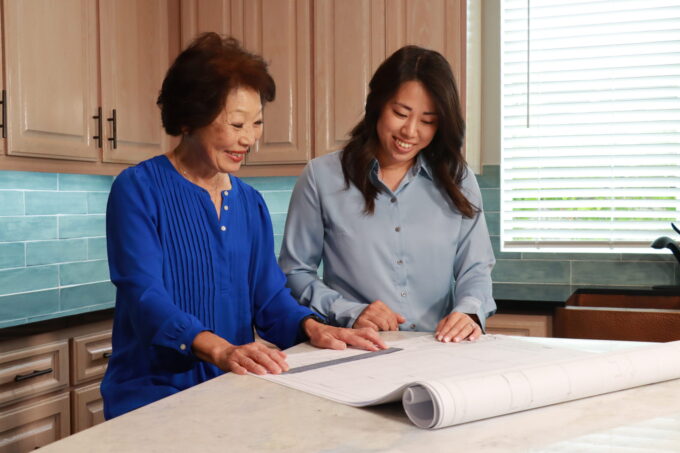 Beverly Ito and Desiree Kitagawa sitting at kitchen counter looking at site plans