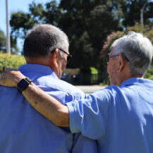 two male friends one having arms around the other