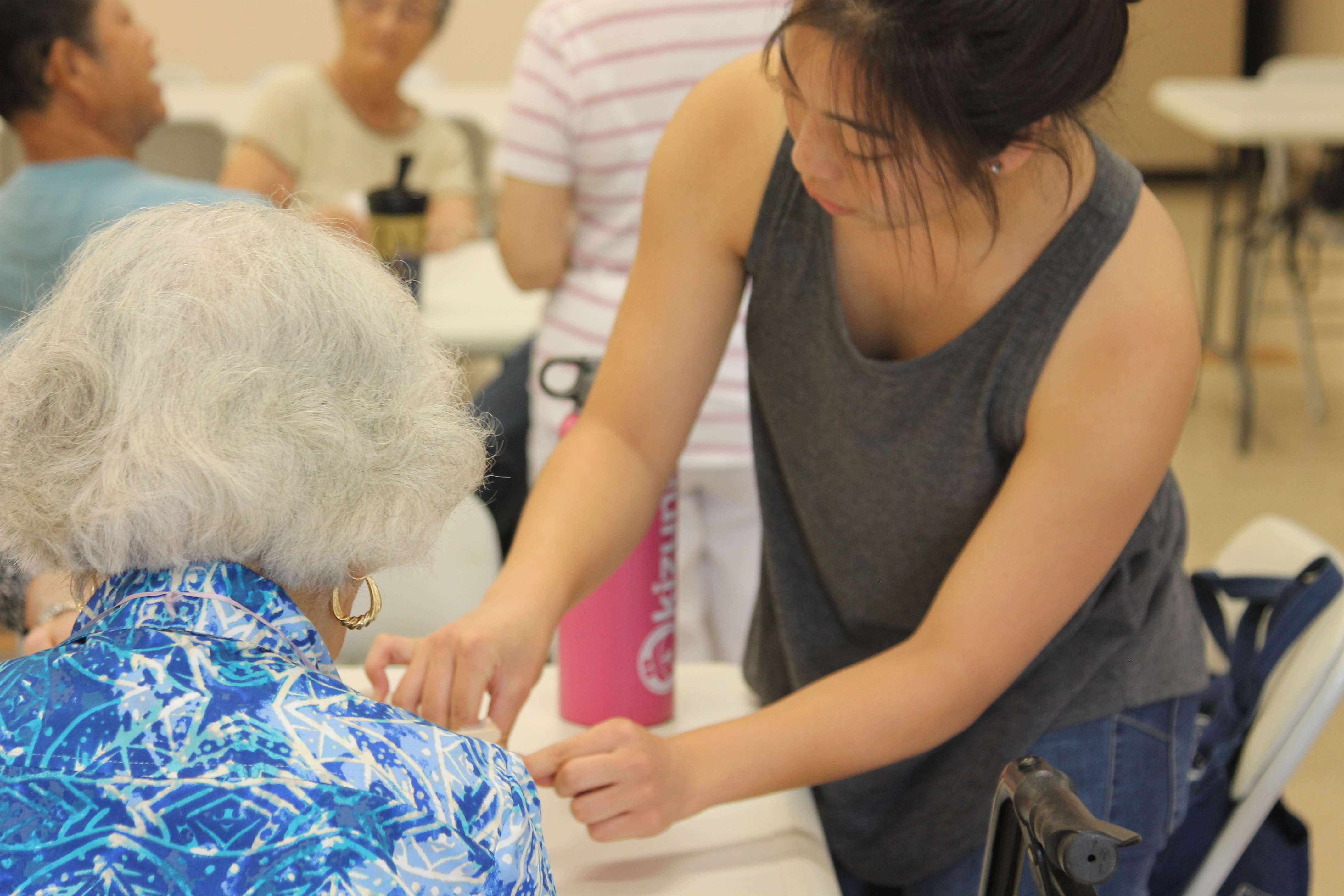 Younger woman standing and caring for older woman sitting.