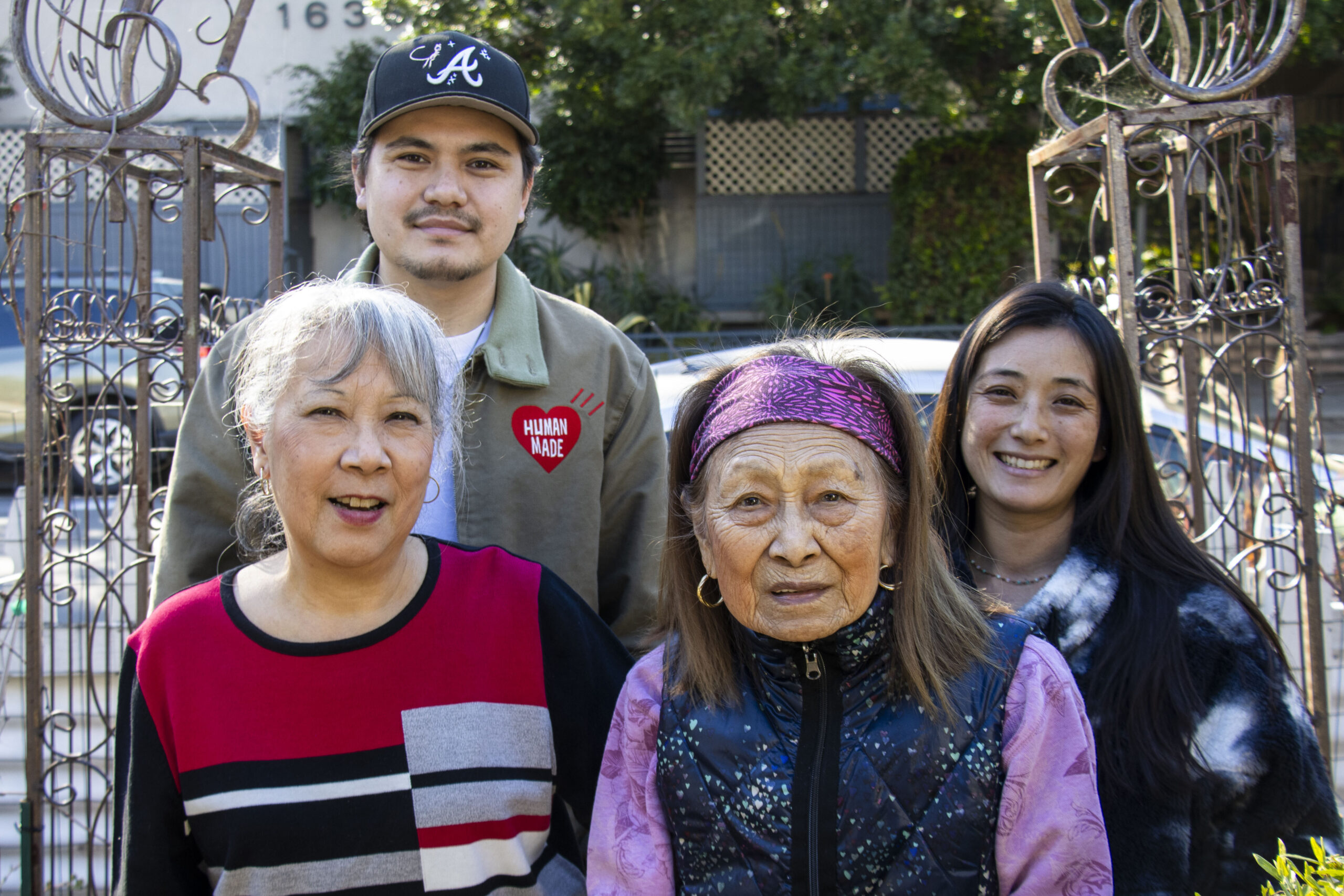 family photo of one man with a black hat, older woman with red sweater, older woman with pink bandana, young woman with tie die sweater