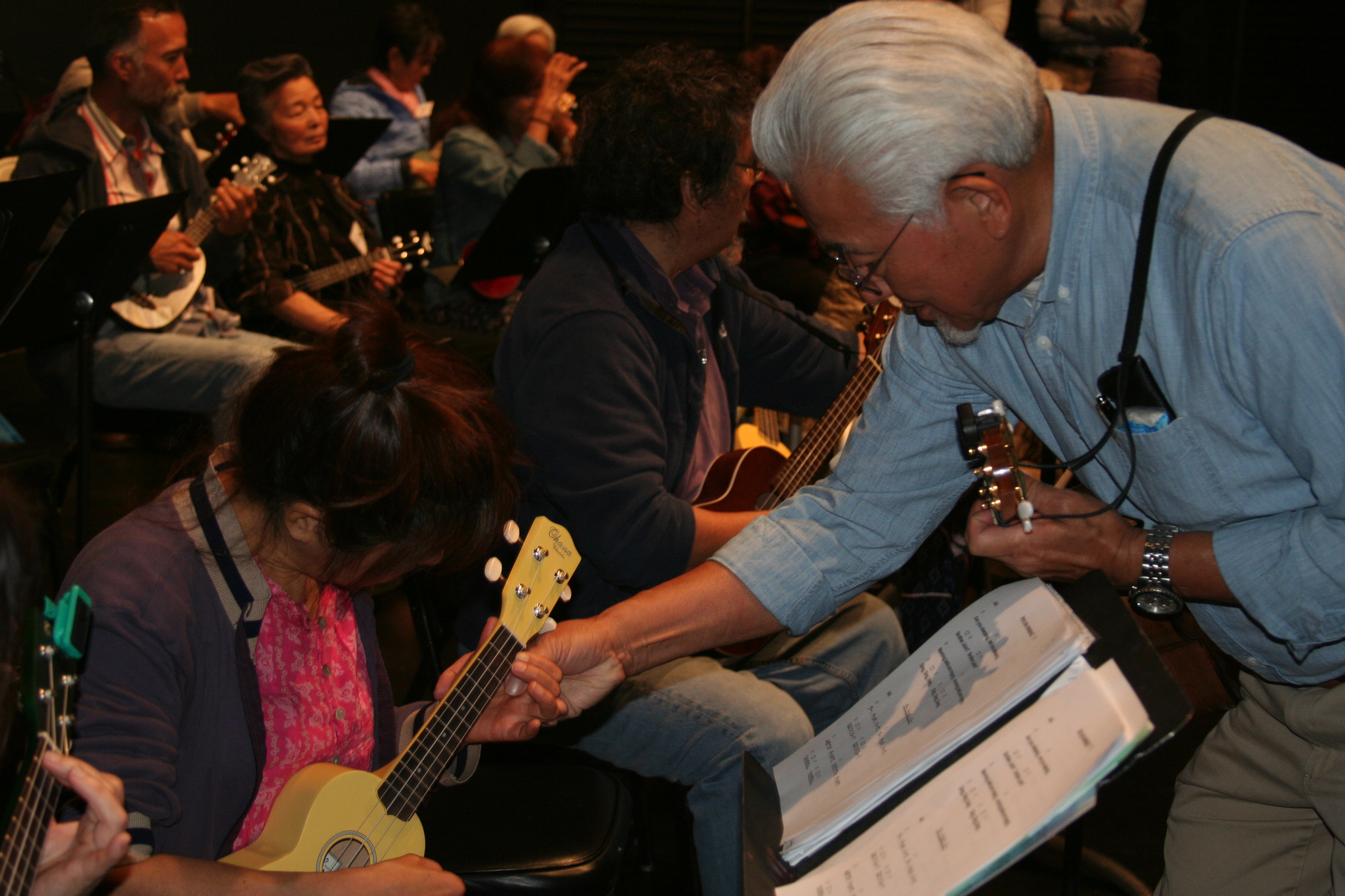 Adult man helps adult woman play ukulele