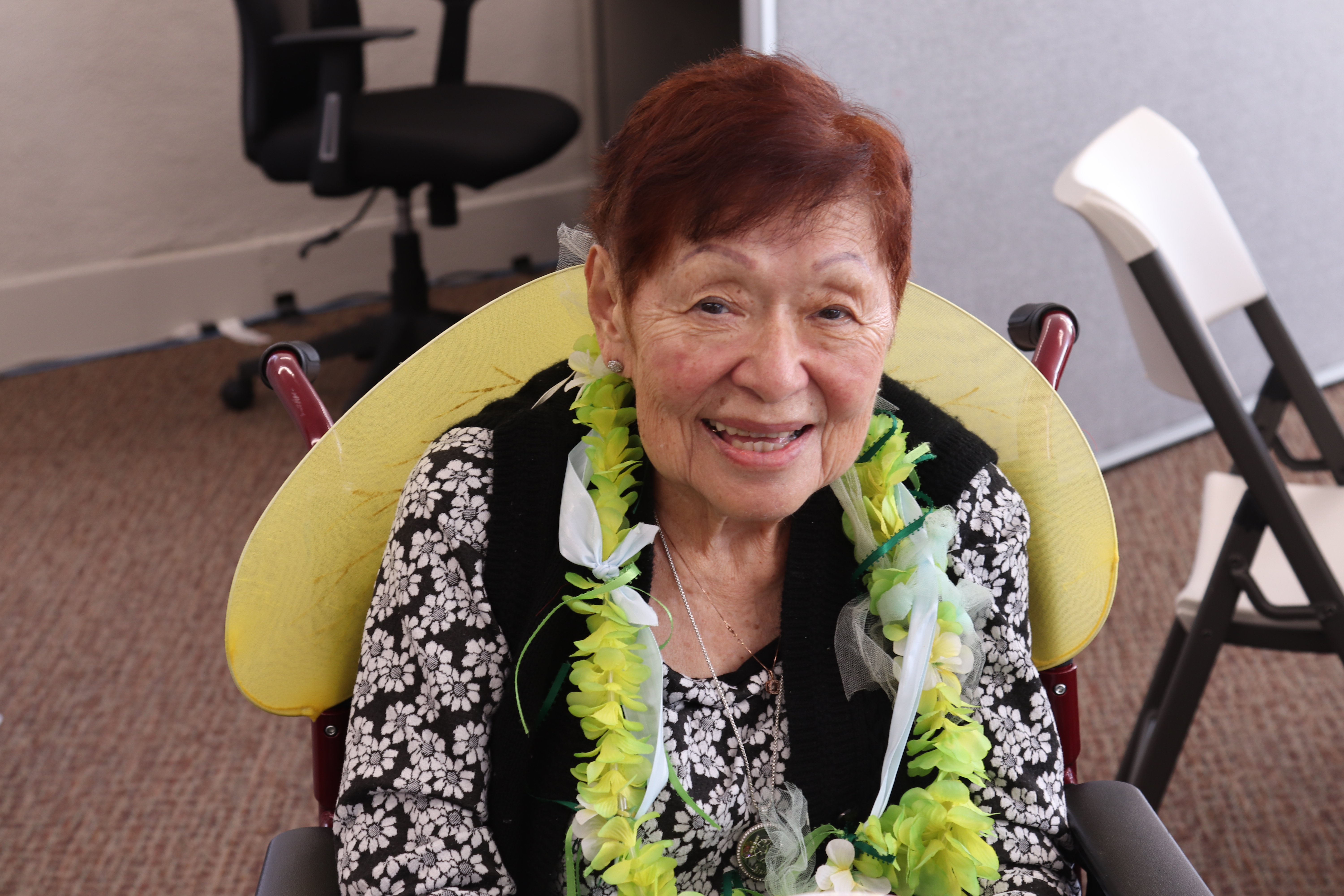 Older adult woman wearing a flower lei around her neck