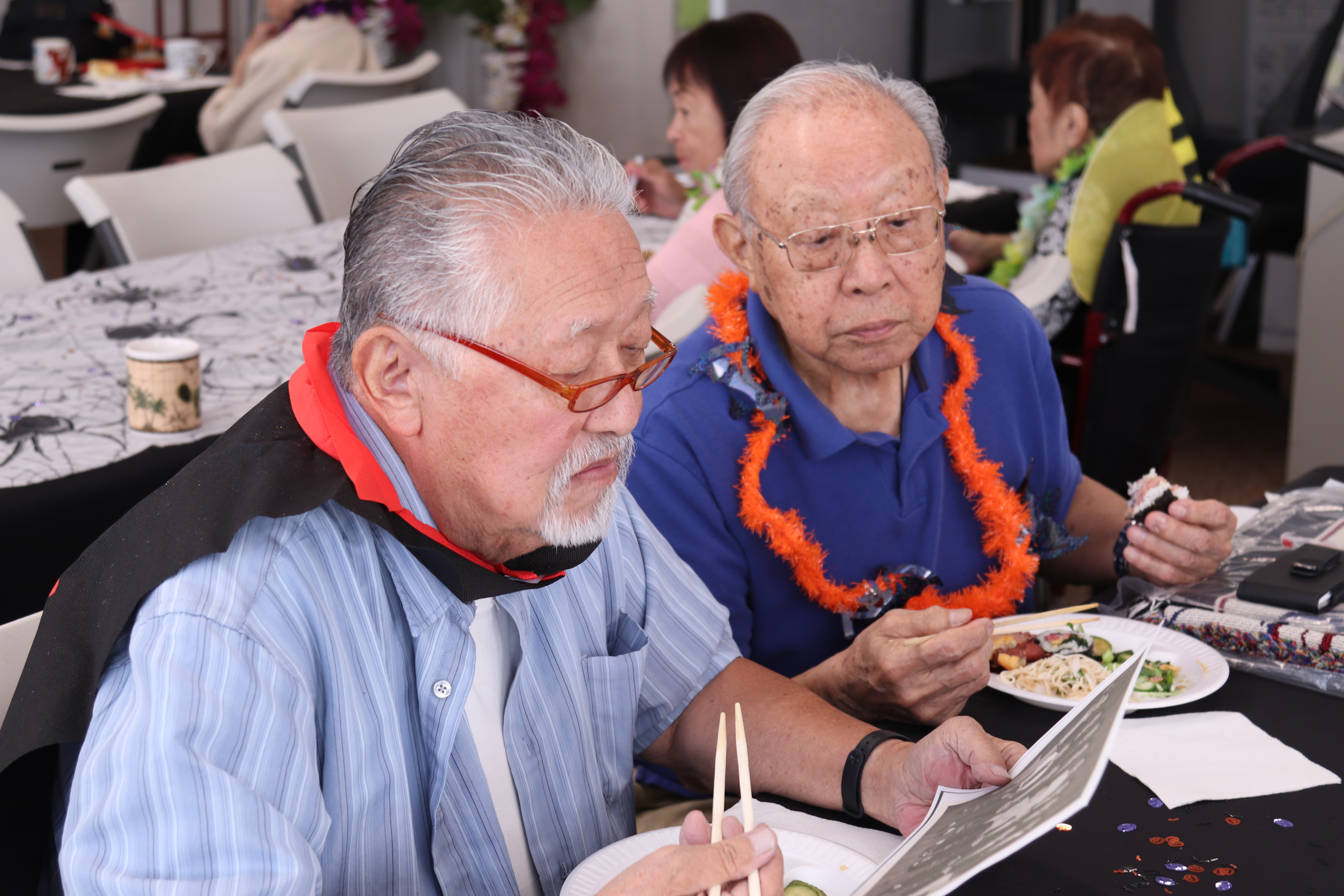 Two older adult men look together at a photo