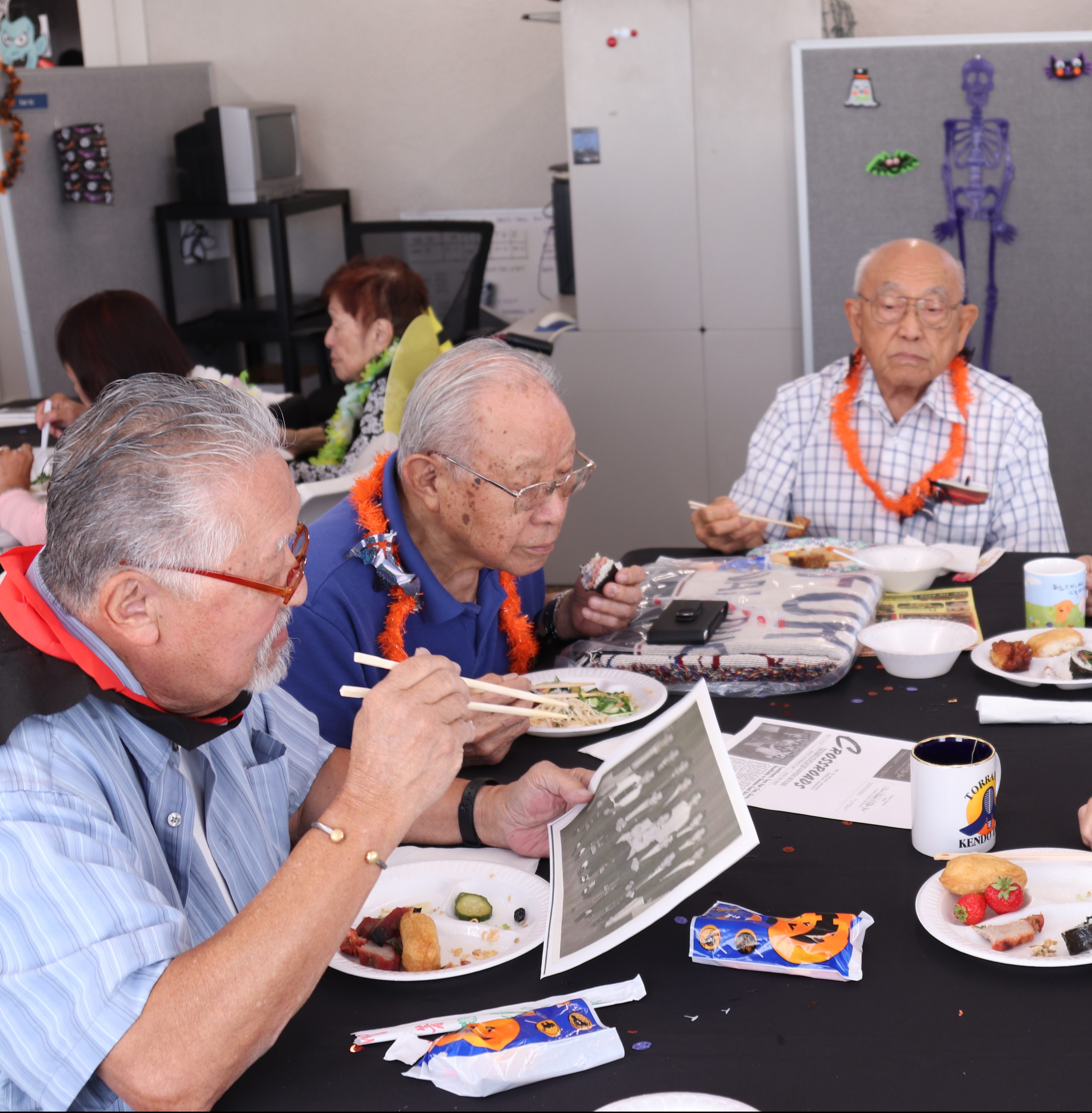 Older adults eating with chopsticks while reading