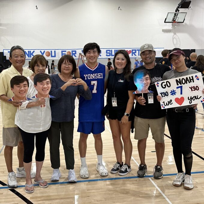 family smiling in a school gym holding signs