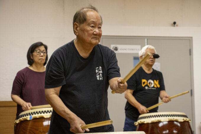 man in black tshirt playing taiko drums