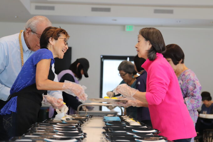 a woman in pink and a woman in blue talking to each other