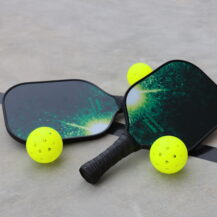 two pickleball paddles and three pickleball balls