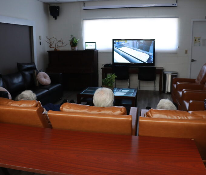 three people sitting down on chairs watching TV