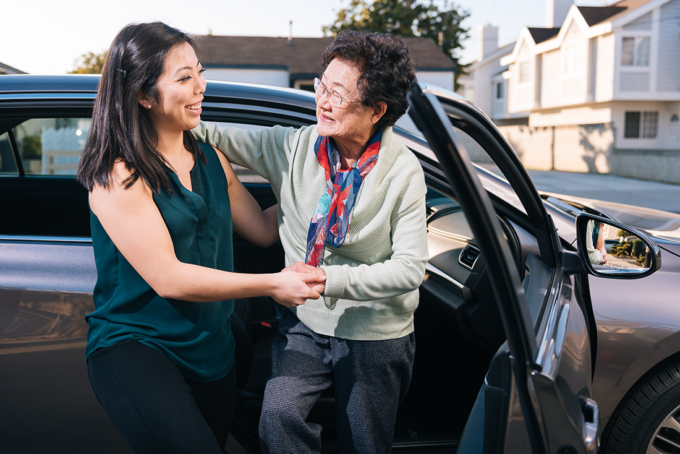 woman helping older adult out of car