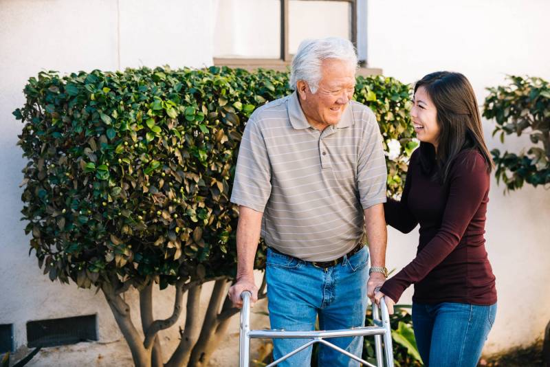 older adult on a walker and young caregiver looking at each other