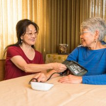caregiver taking blood pressure for older adult