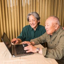 caregiver assisting older adult with laptop