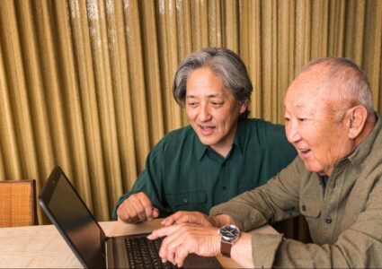 older adult and caregiver searching on the computer