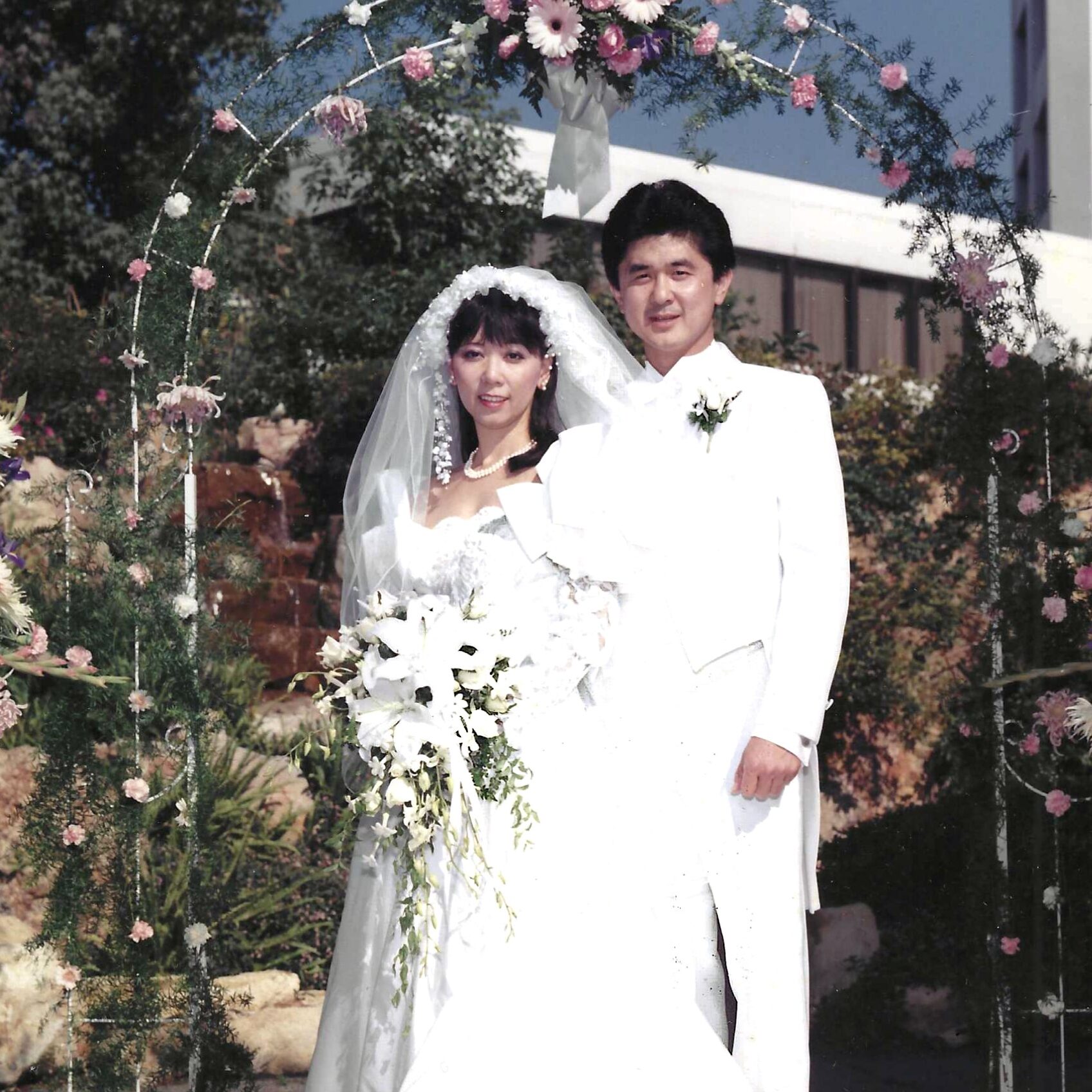out door wedding photo of woman with long wedding dress and man in white tux